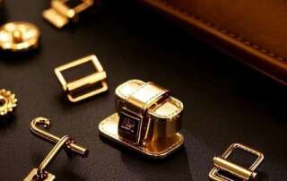 Gold turn locks and hook clasps displayed next to a leather bag.
