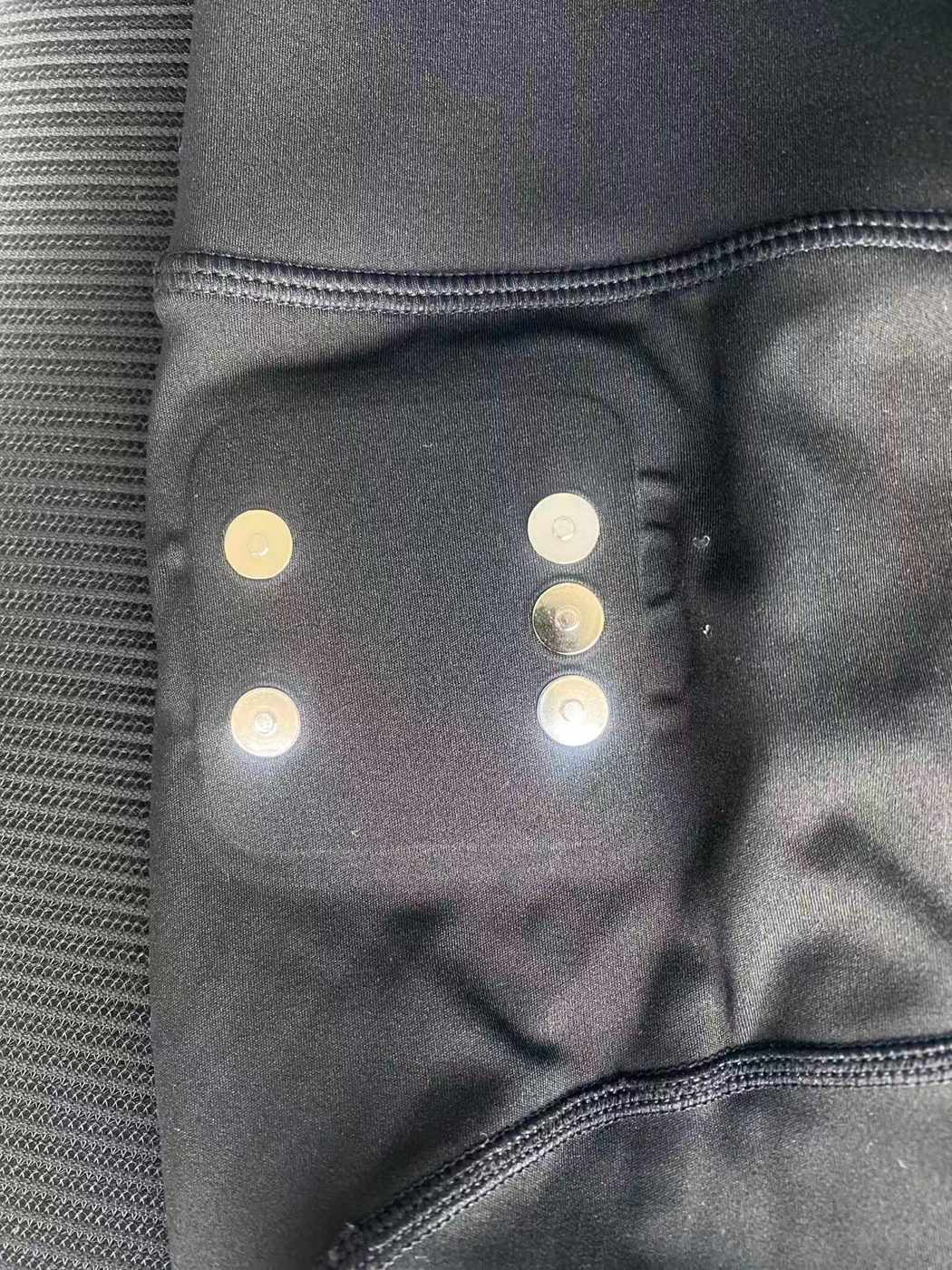 Five round metal contacts mounted in dark stretch fabric